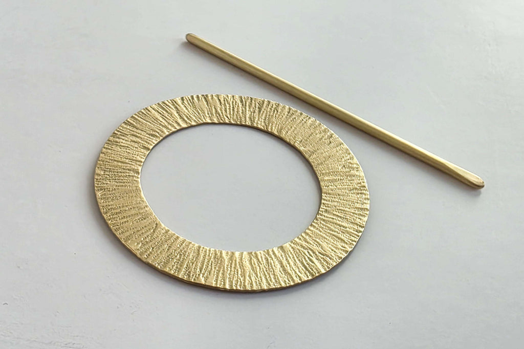 Gold circular metal object on a light gray background