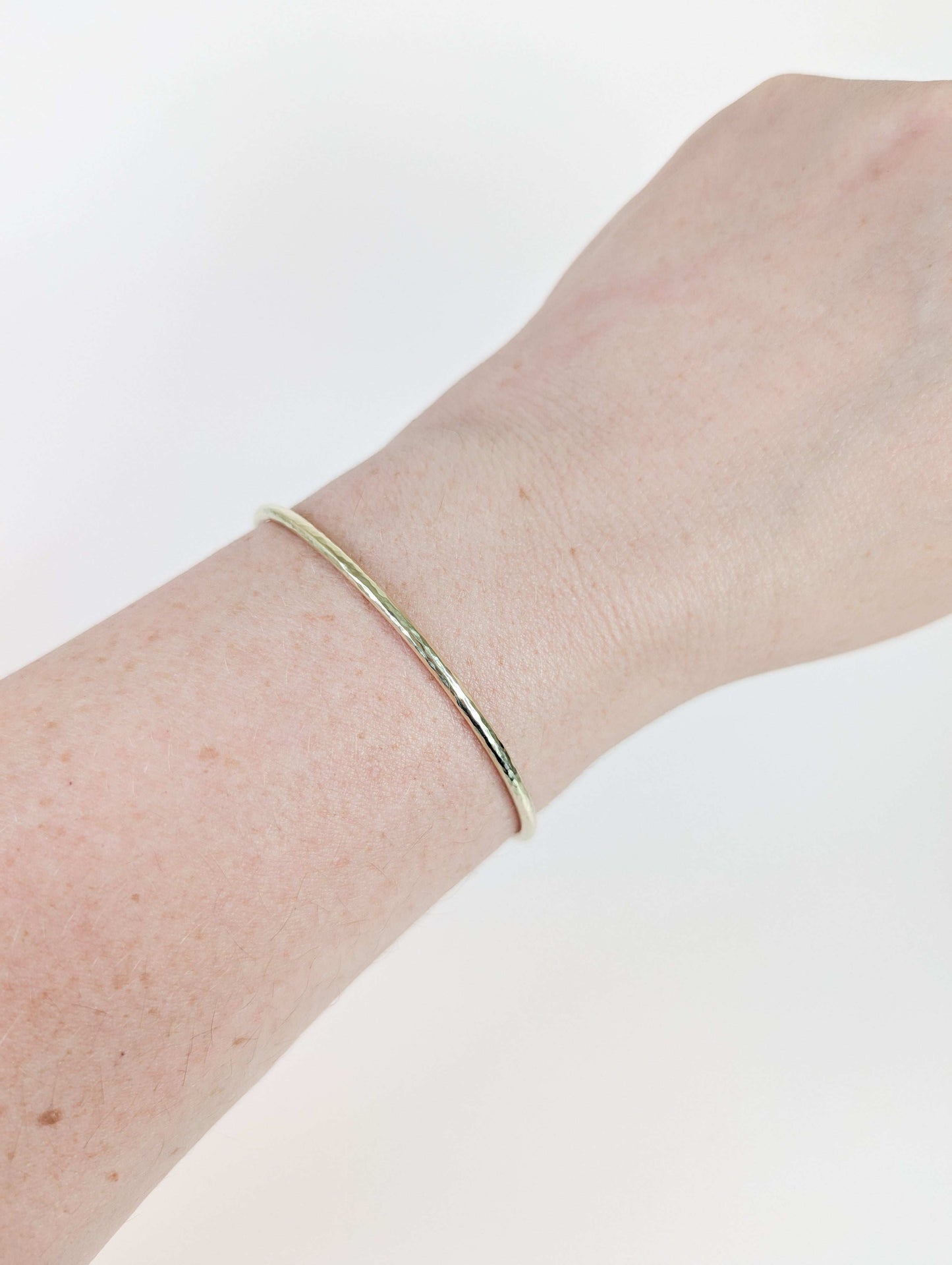 Gold bracelet on a wrist against a white background