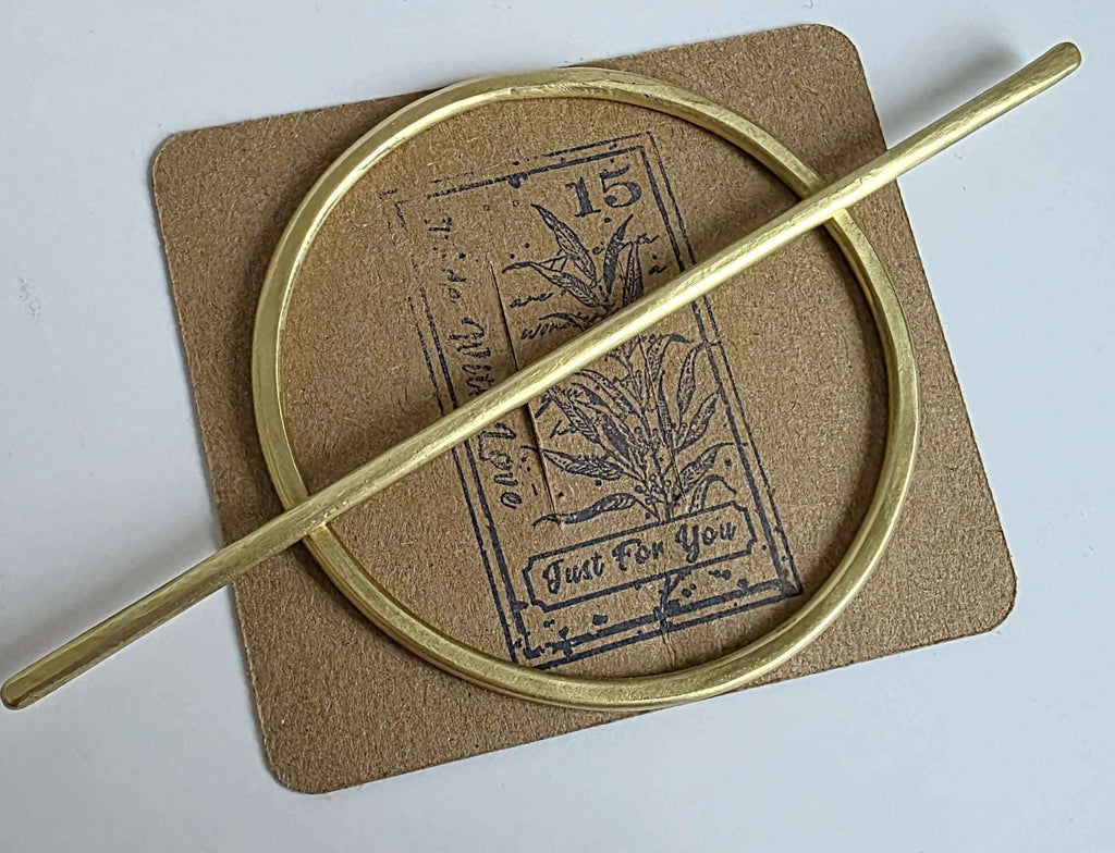 brass Gold hair barrette and stick on a textured brown card with text and graphics