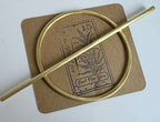 brass Gold hair barrette and stick on a textured brown card with text and graphics
