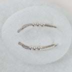 Silver bead ear climber with three small beads on a white background
