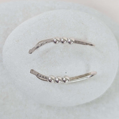 Silver bead ear climber with three small beads on a white background