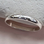 Sterling Silver ring with hand stamped star pattern on a light gray stone surface