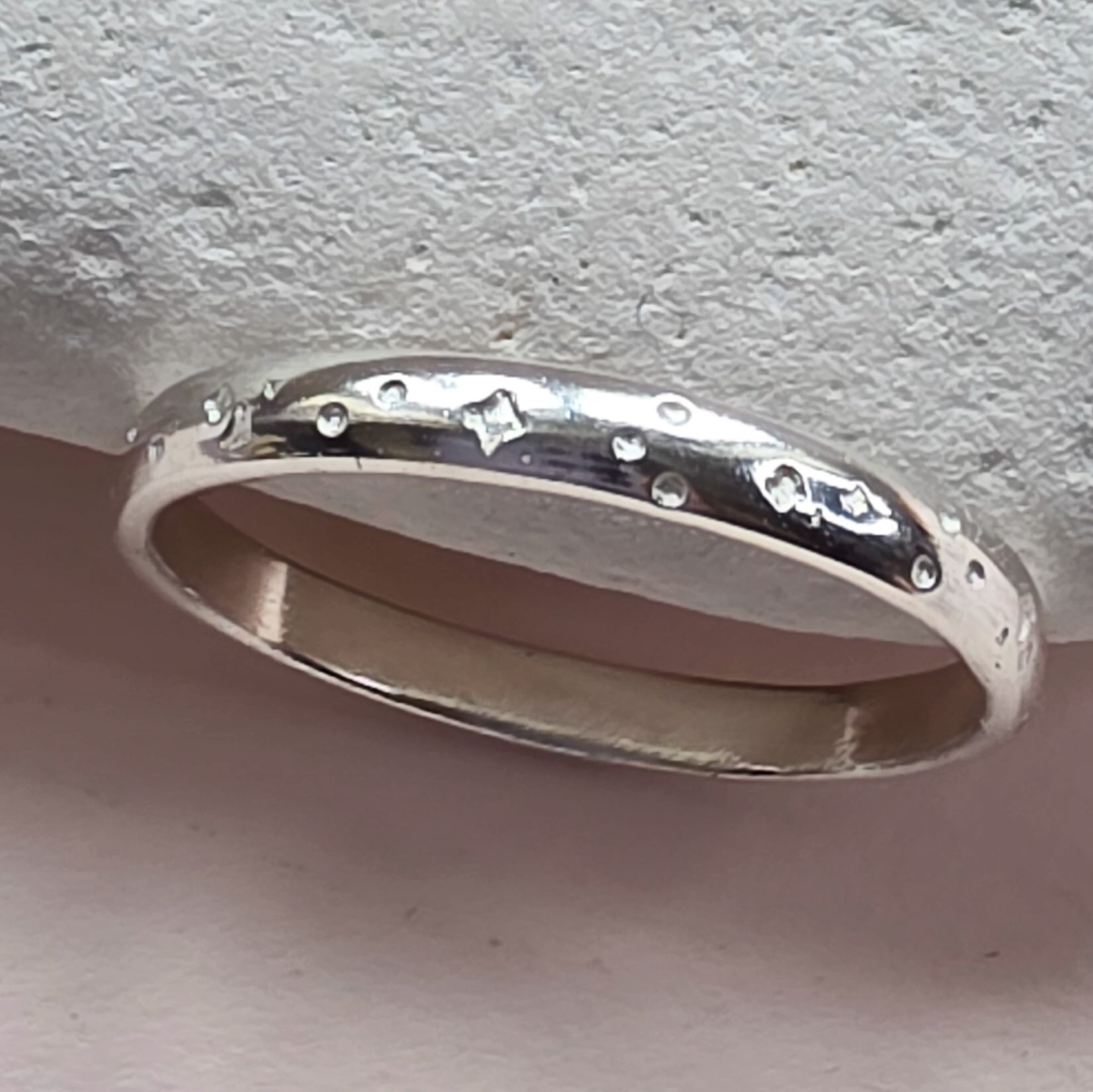 Sterling Silver ring with hand stamped star pattern on a light gray stone surface