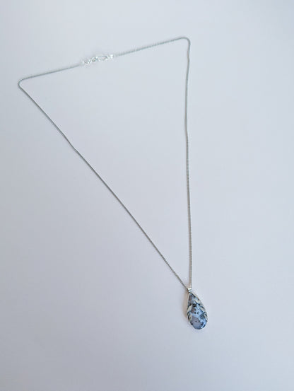 Dendritic snow agate leaf Necklace with a pendant on a light grey surface