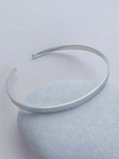 Silver bangle on a light gray background