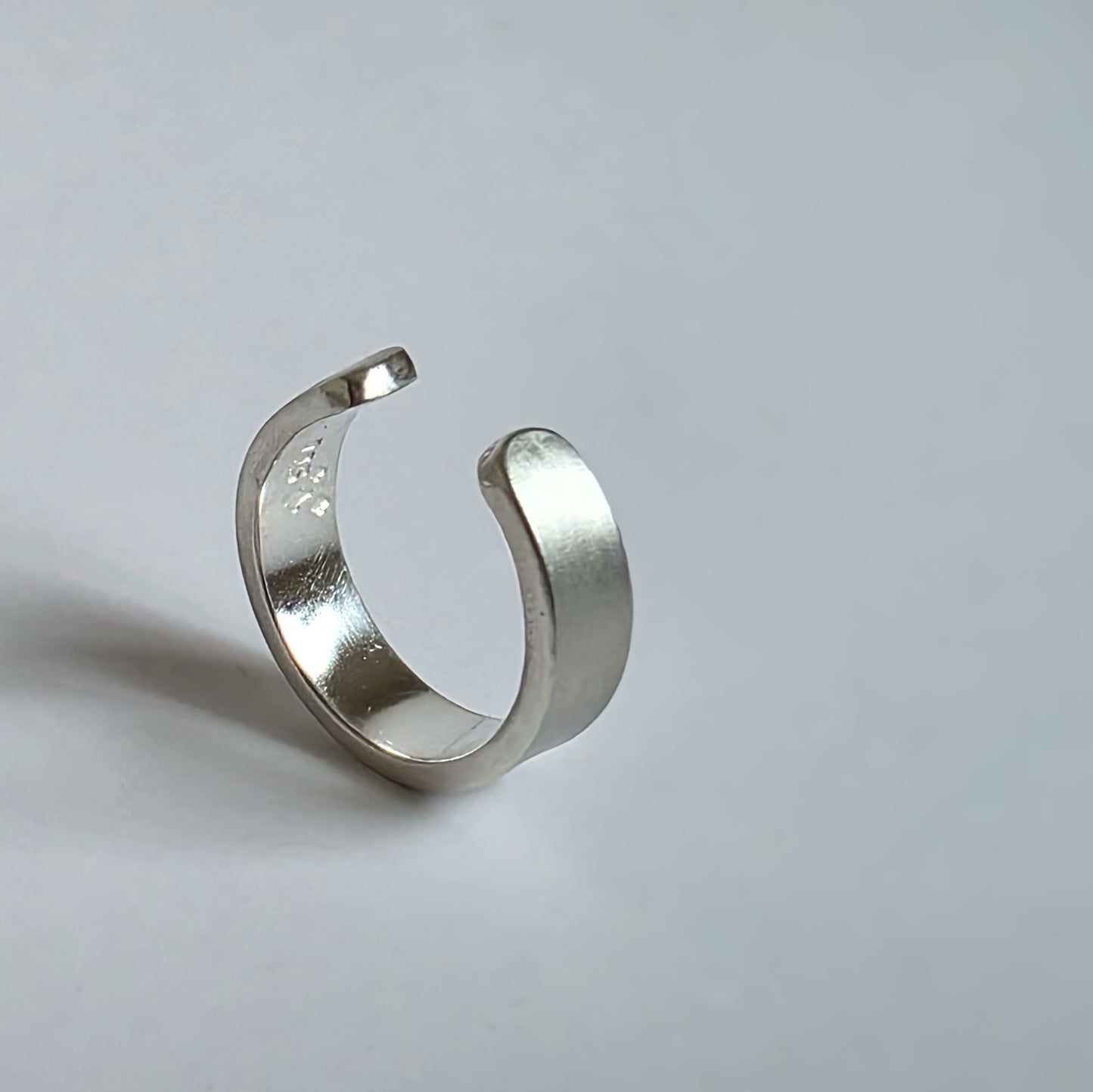 Silver open ring on a light gray background
