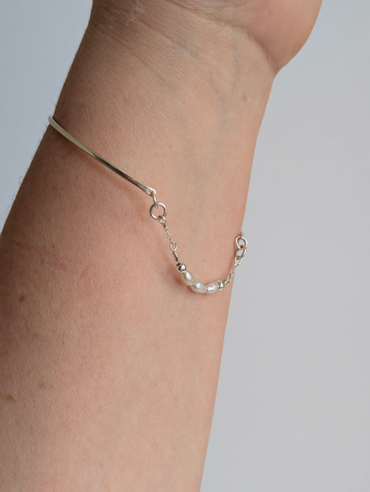 Thin sterling silver dainty cuff bangle with seed pearl bar chain - worn on wrist showing back pearl chain detal