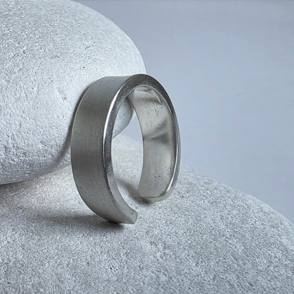 Silver ear cuff on a textured stone surface with a neutral background