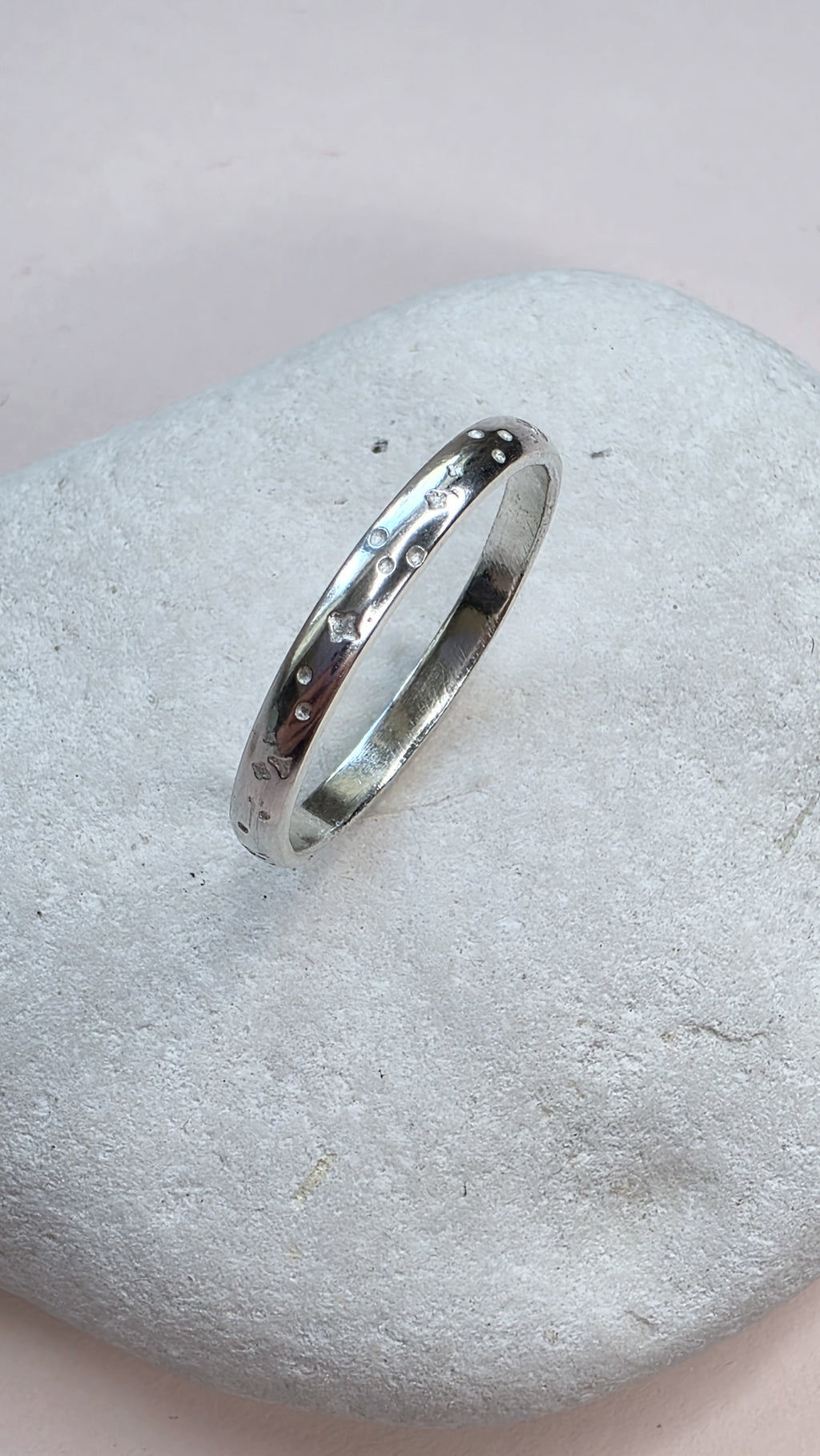 Sterling Silver ring with hand stamped star pattern on a light gray stone surface