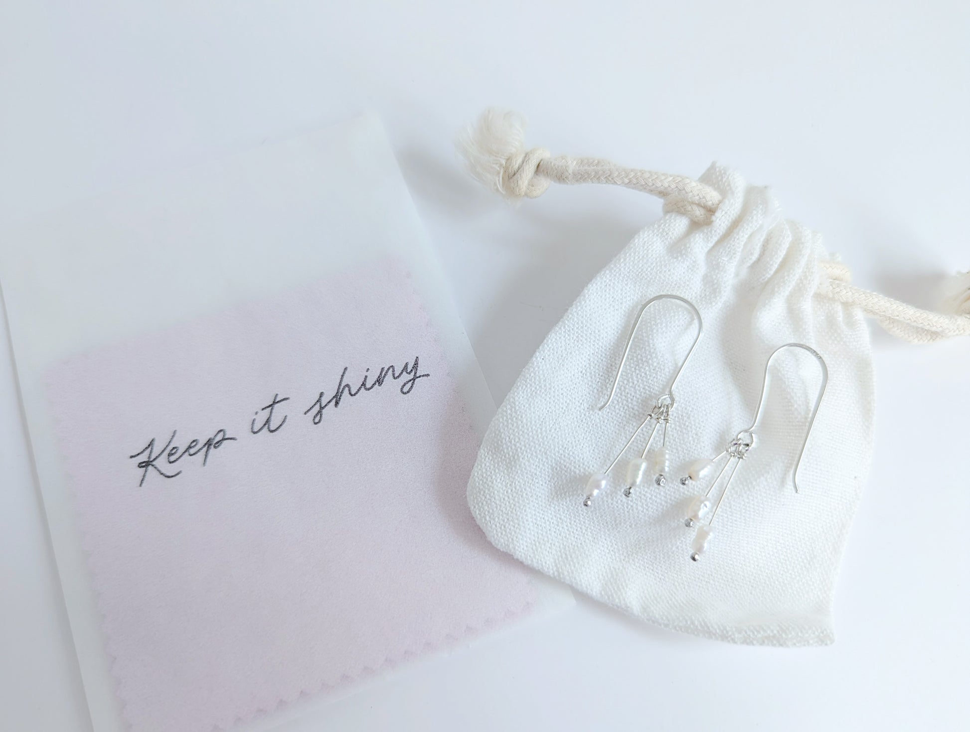 Dainty freshwater seed pearl dangle cascade drop earrings in Sterling silver - shows packaging including white cotton drawstring bag and polishing cloths 