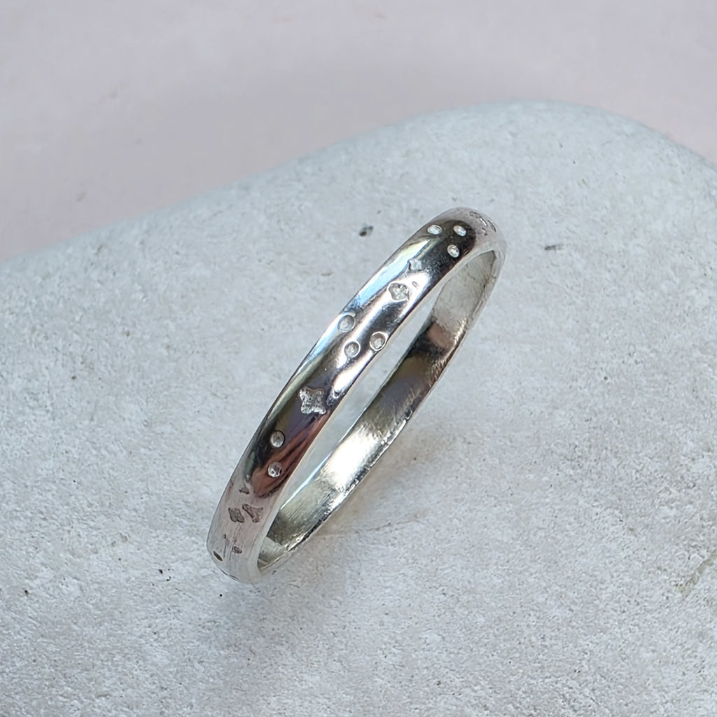 Sterling Silver ring with hand stamped star pattern on a light gray stone surface