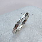 Sterling Silver ring with hand stamped star pattern on a light gray stone surface