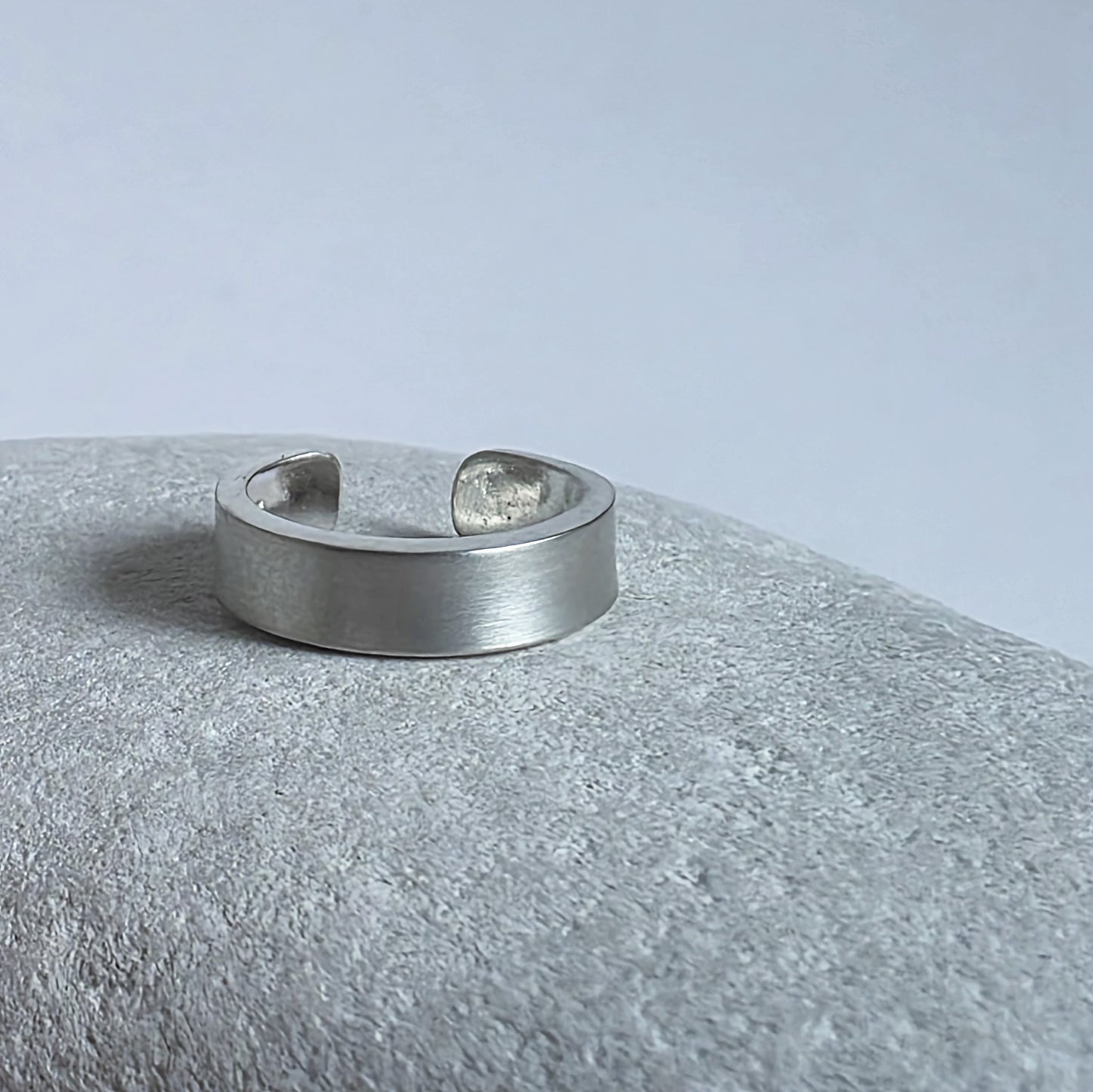 Silver ring on a textured gray surface with a light gray background