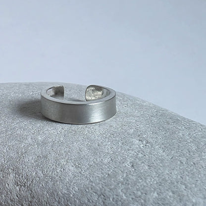 Silver ring on a textured gray surface with a light gray background