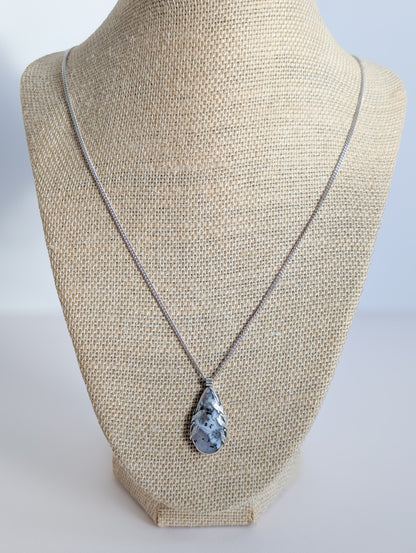 Dendritic snow agate leaf Necklace on a mannequin bust against a plain background