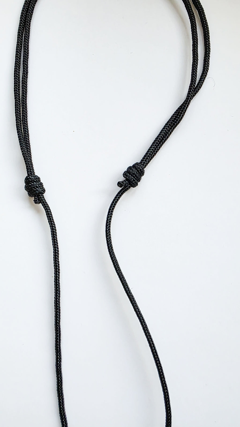 adjustable black cord necklace with a knot on a white background