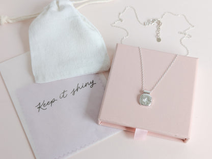 Necklace with pendant in a pink jewelry box on a light surface