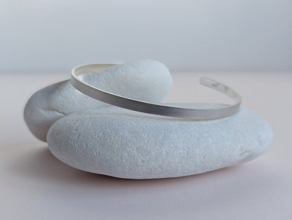 Silver bracelet on a textured stone surface with a light gray background