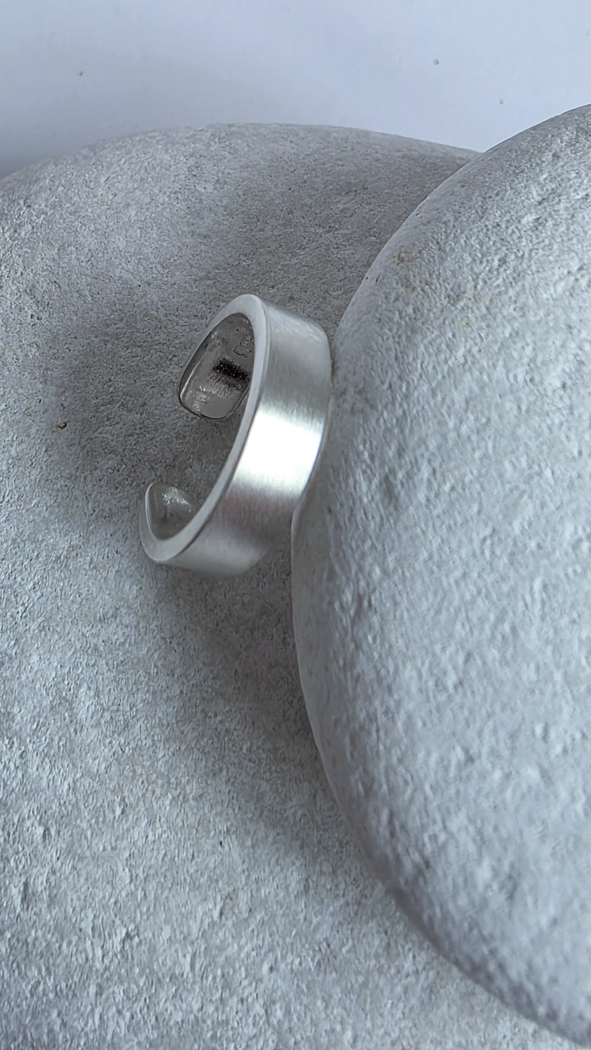 Silver ear cuff on a textured gray surface