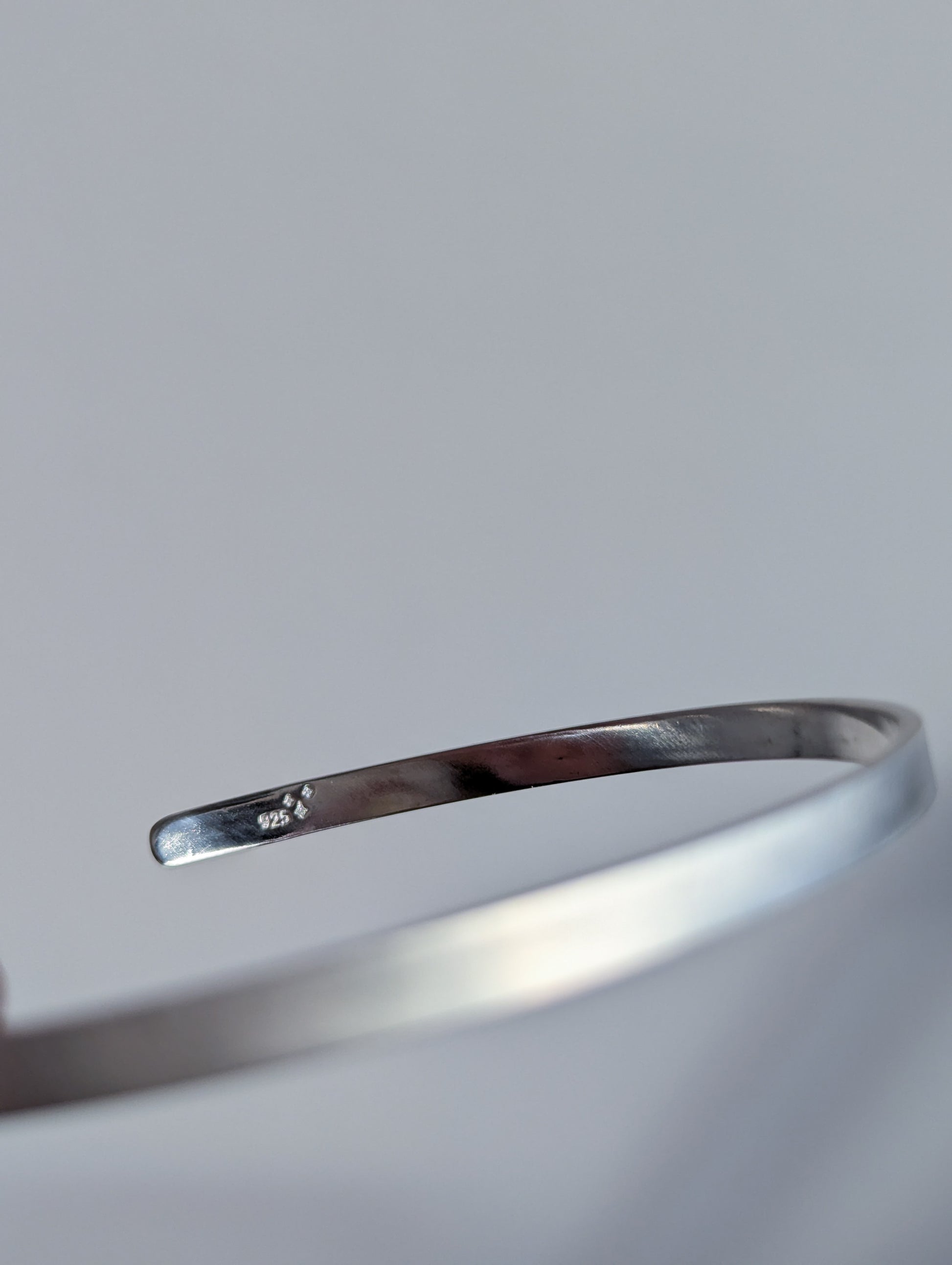 Silver bangle on a light gray background