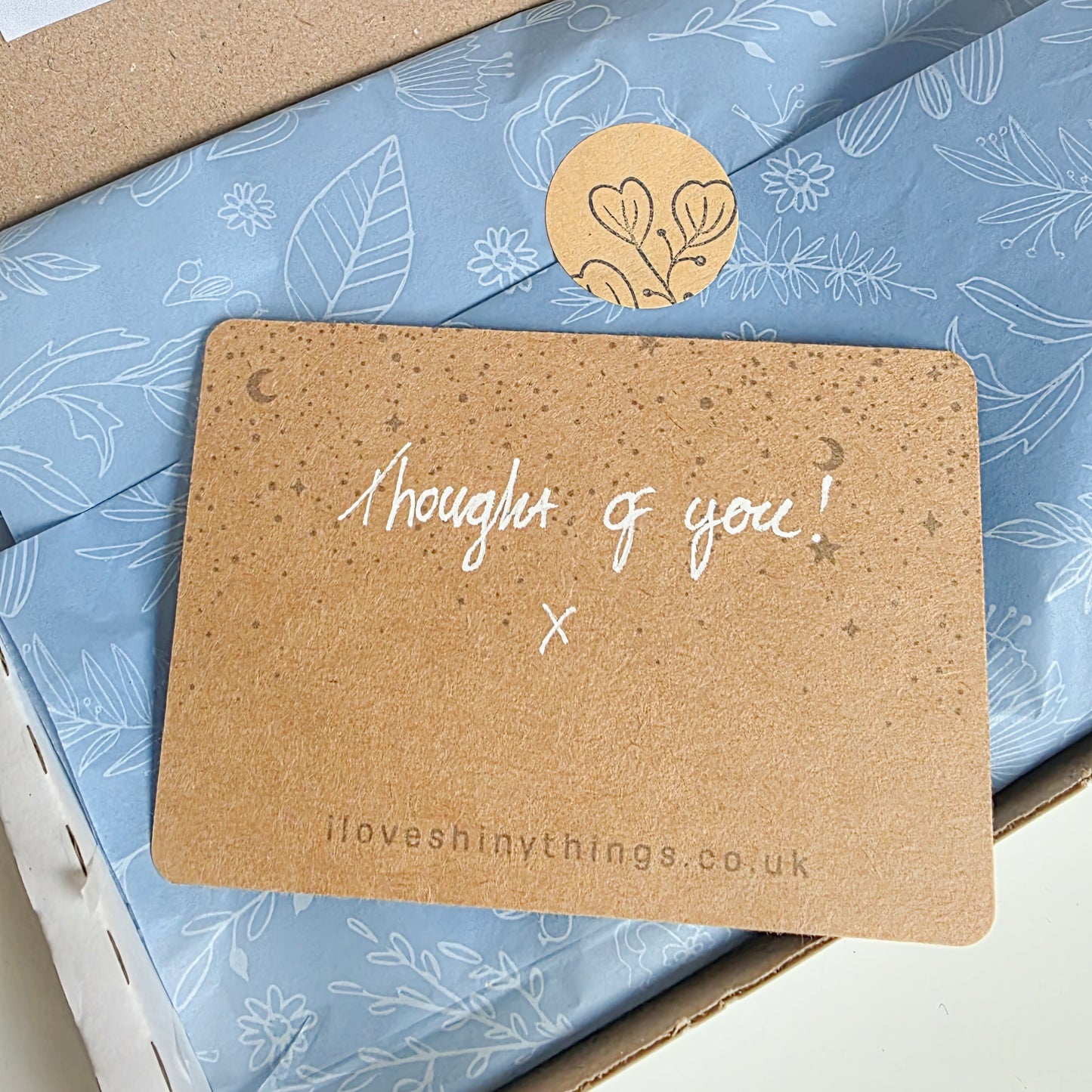 Kraft paper card with 'Thought of you!' message on a blue floral-patterned box.