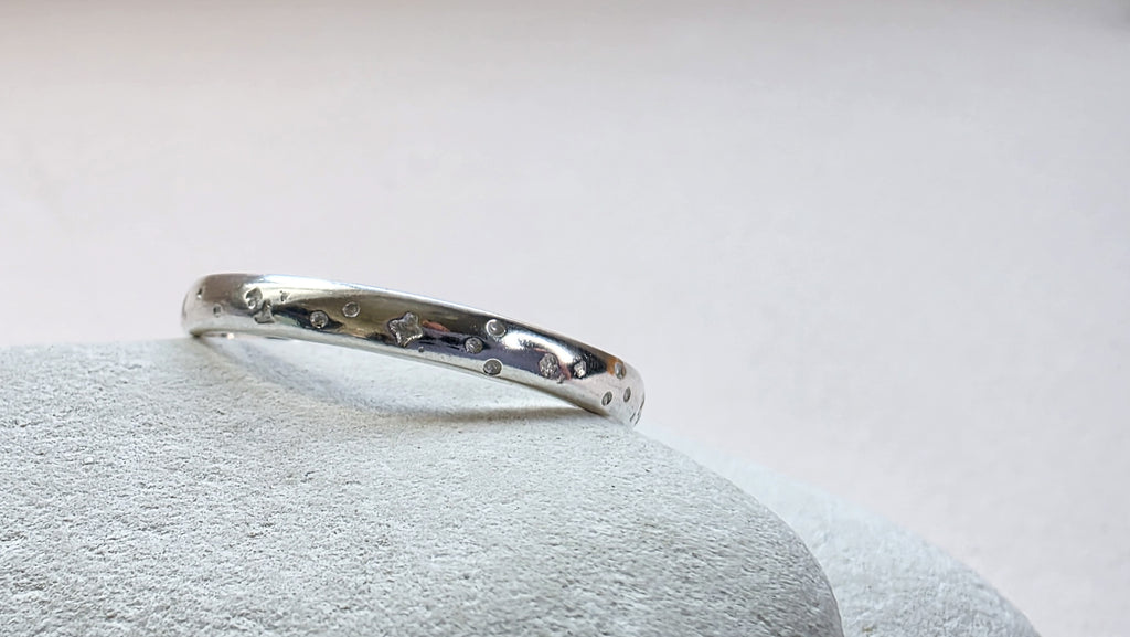 Sterling Silver ring with hand stamped star pattern on a light gray stone surface