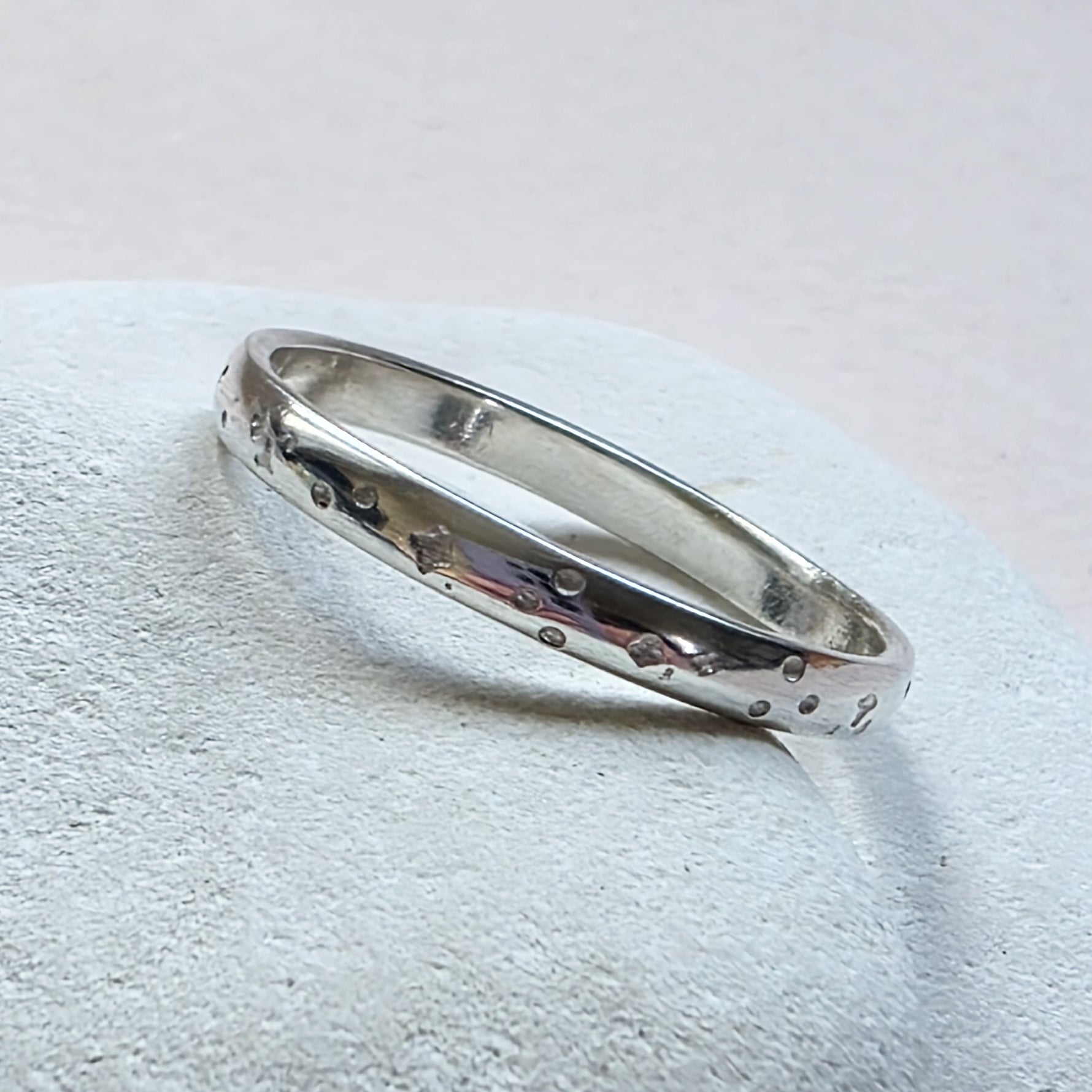 Sterling Silver ring with hand stamped star pattern on a light gray stone surface