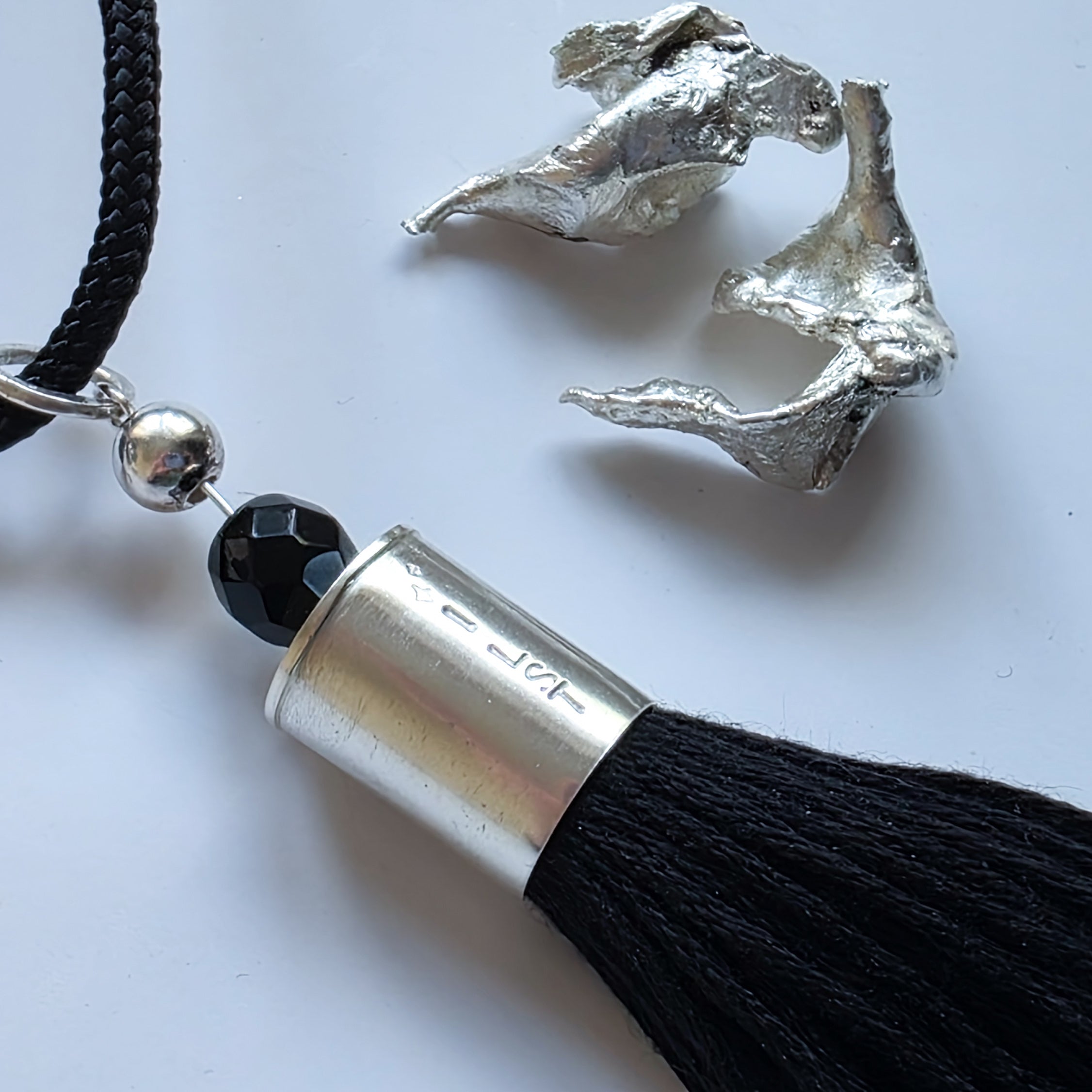 sterling Silver tassel necklace with black tassel and black bead on a white background