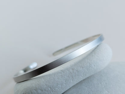 brushed Silver cuff bangle on a light grey background