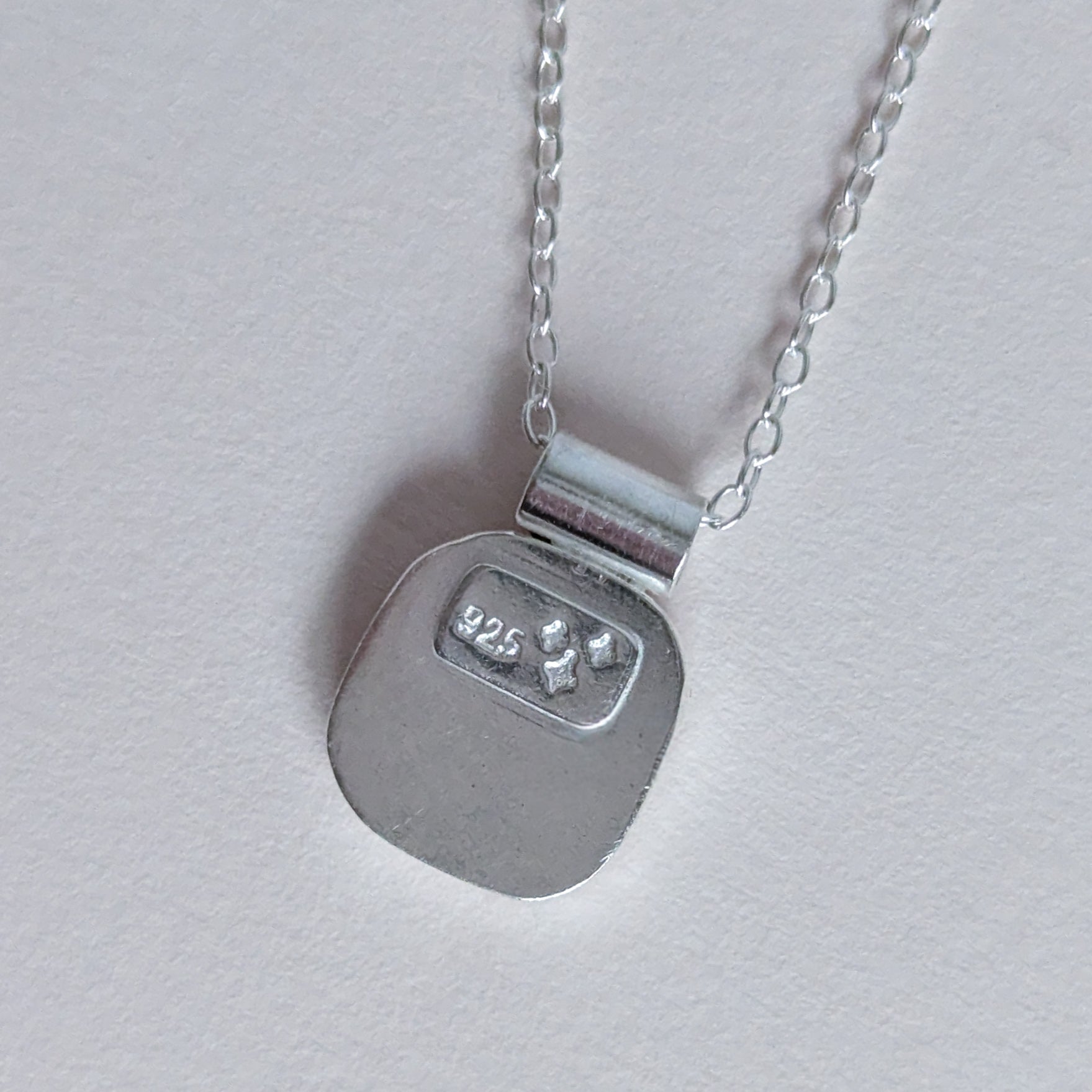 Silver necklace with a 925 sterling silver stamp on a light gray background