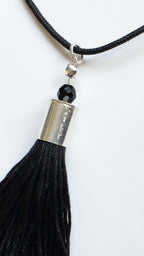 Black tassel necklace with silver accent and black bead on a white background