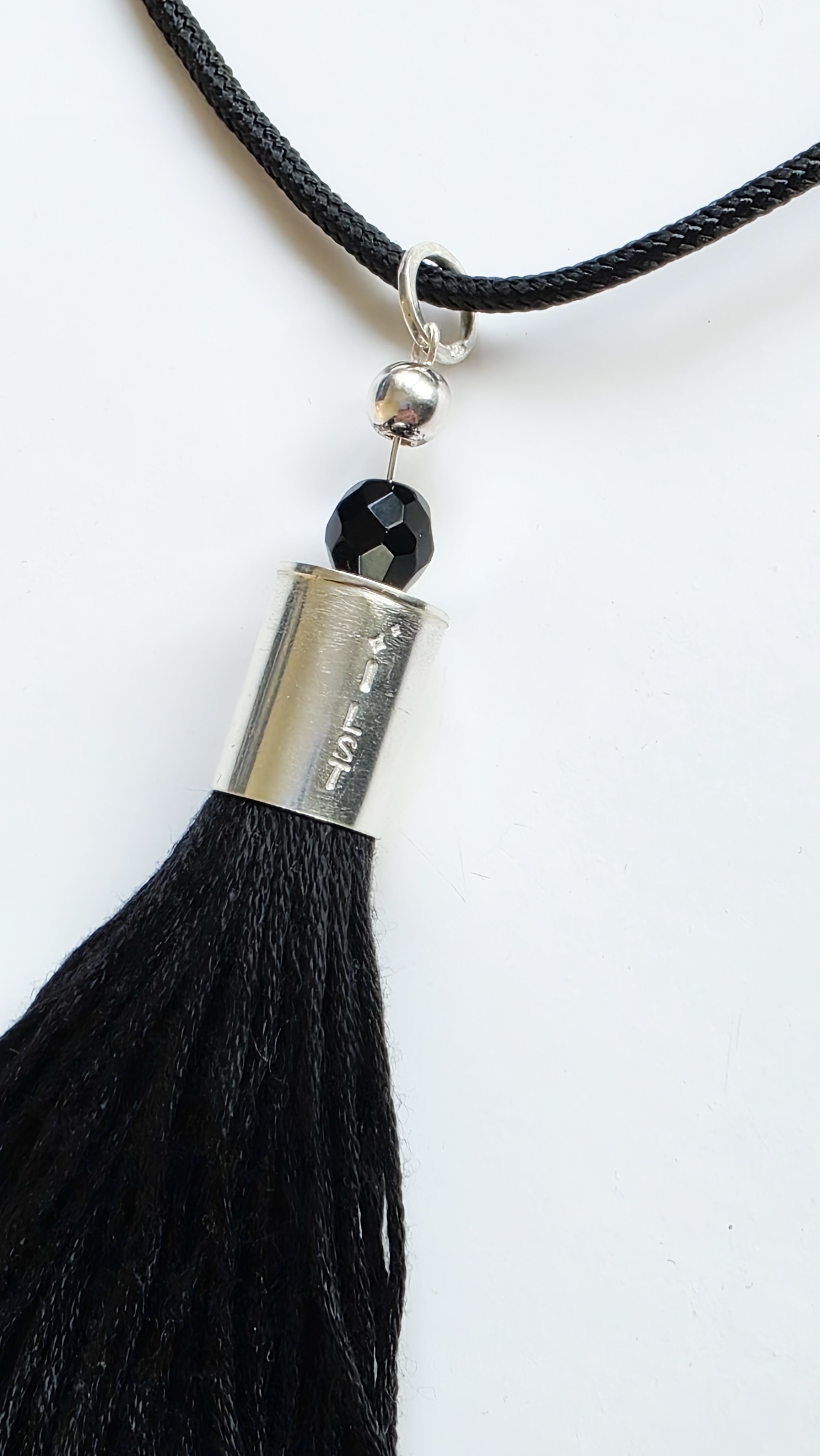 Black tassel necklace with silver accent and black bead on a white background