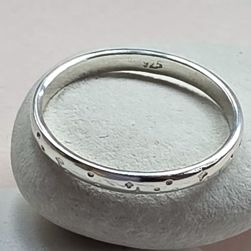 Sterling Silver ring with hand stamped star pattern on a light gray stone surface