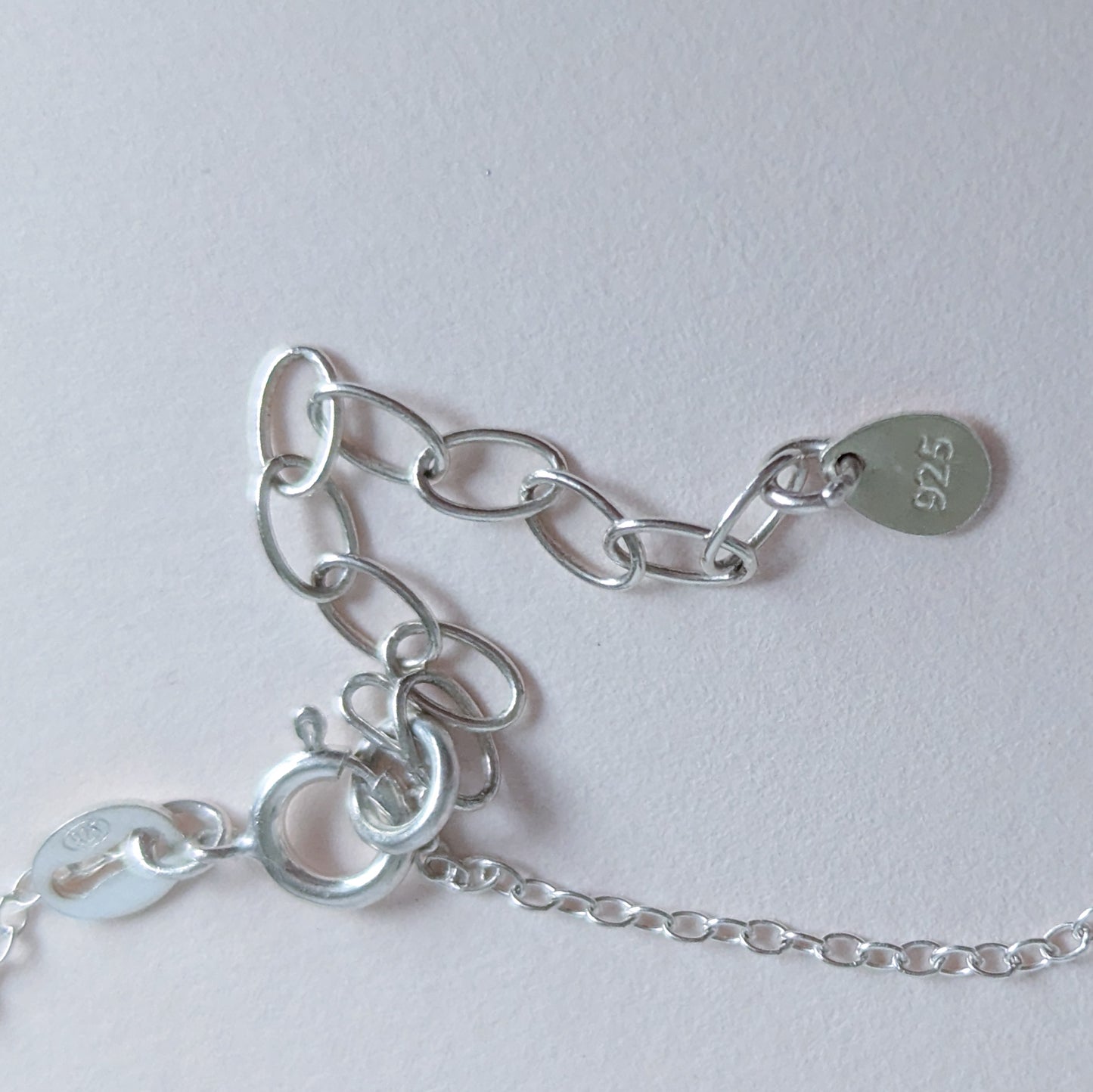 Silver chain bracelet with a tag on a light gray background