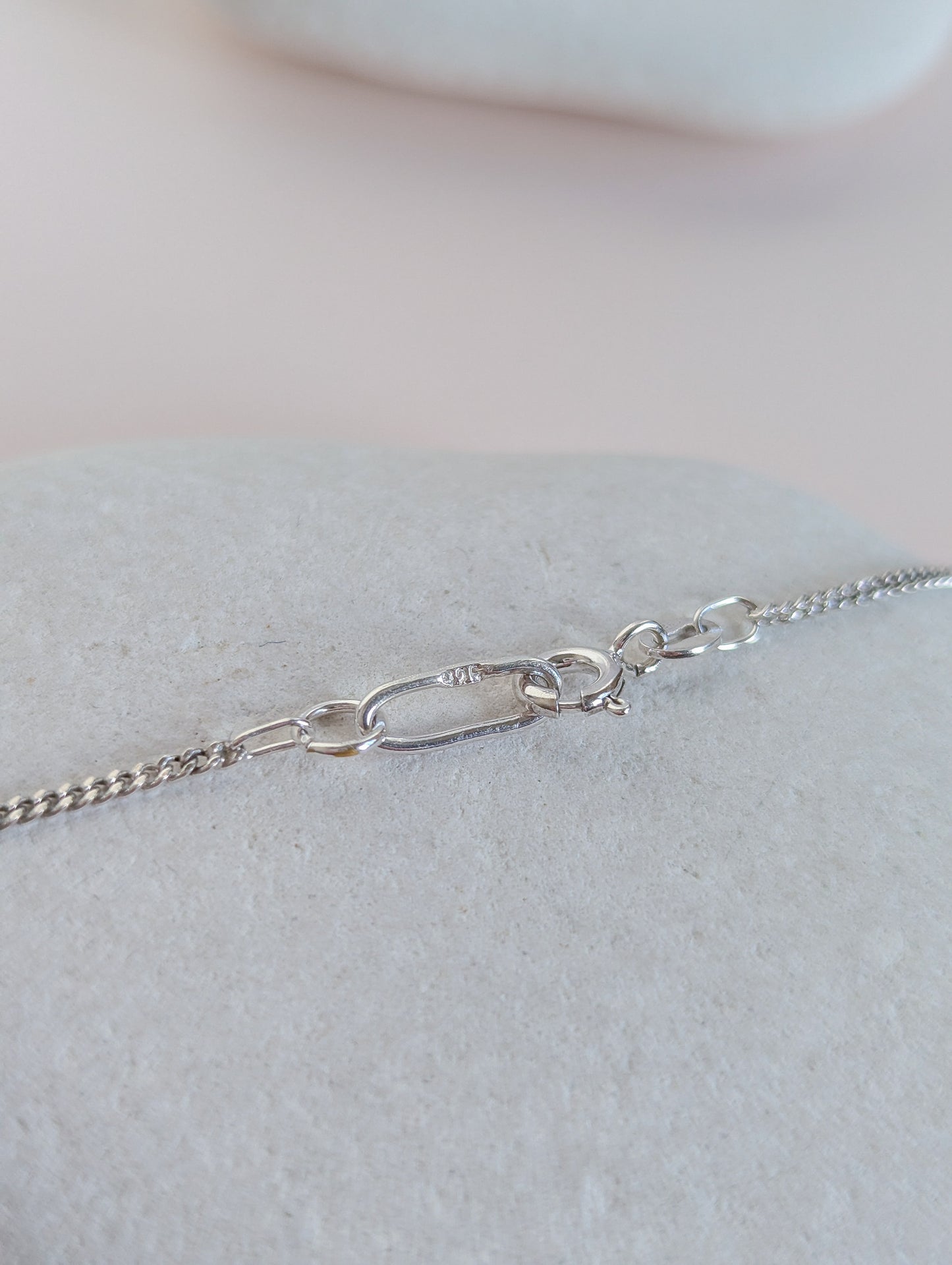 Silver chain necklace on a light gray surface with a neutral background