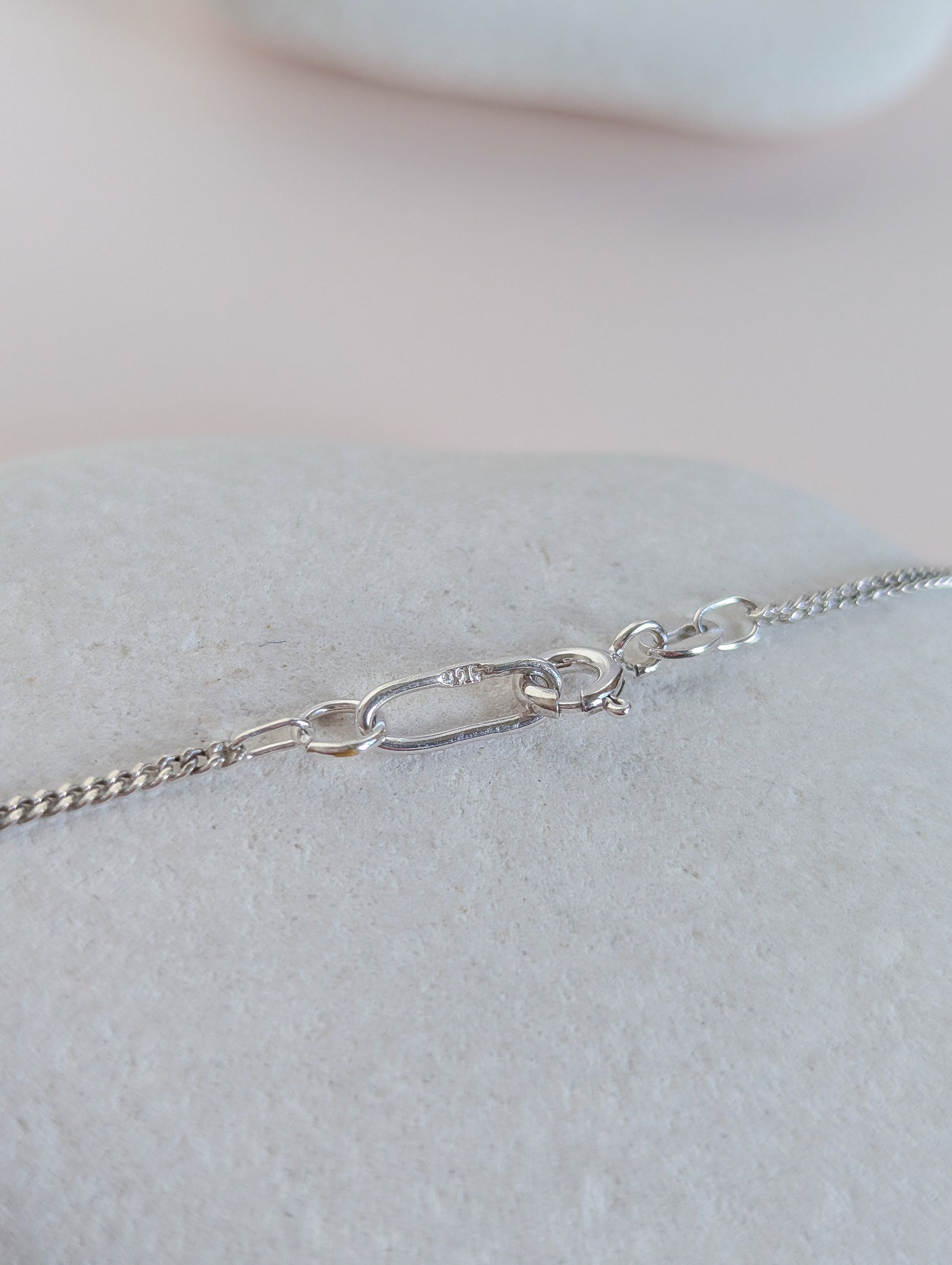 Silver chain necklace on a light gray surface with a neutral background