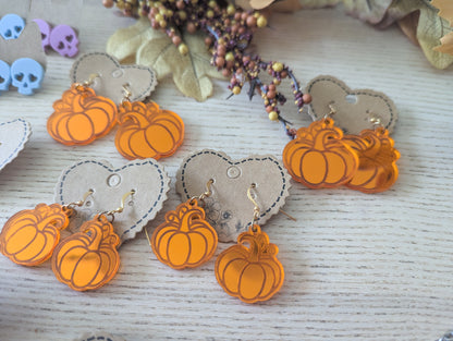 Pumpkin-shaped earrings on heart-shaped pads with a neutral background