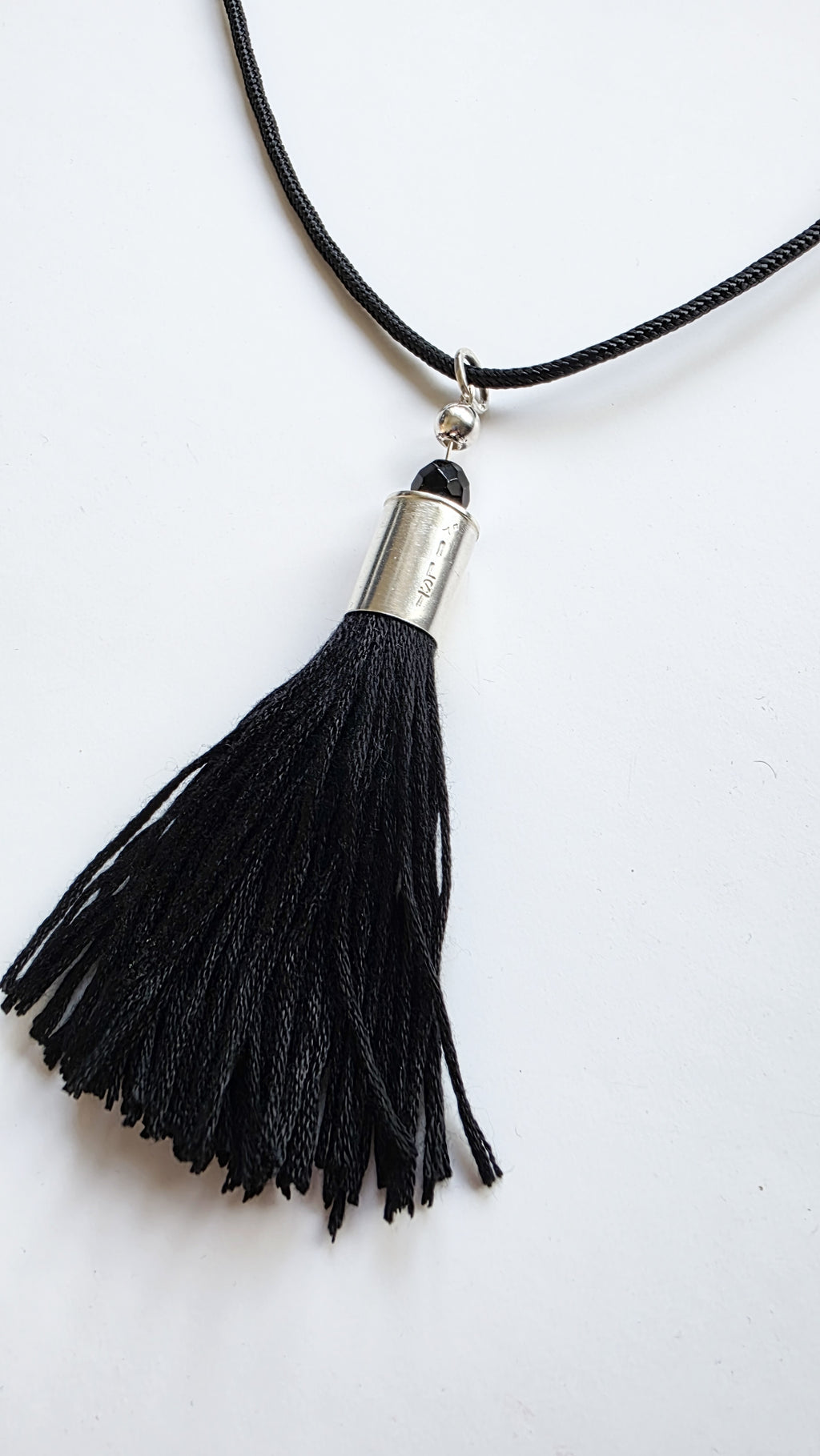 Black tassel necklace with silver accent on a white background
