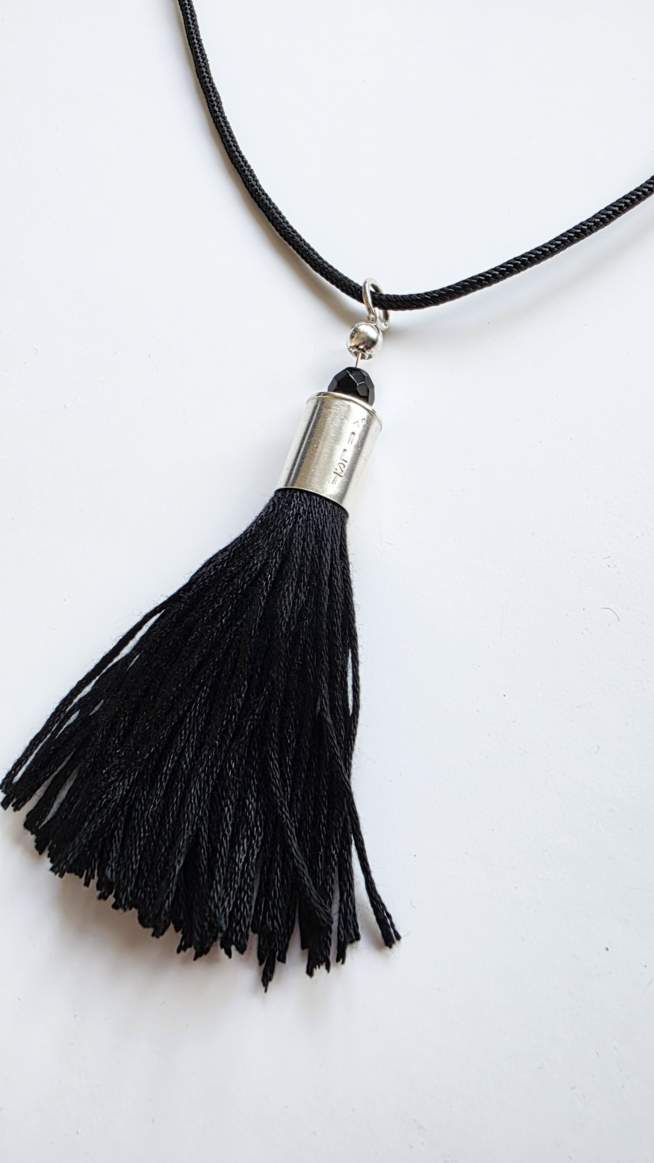 Black tassel necklace with silver accent on a white background