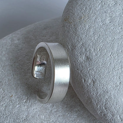 Silver ear cuff on a textured stone surface