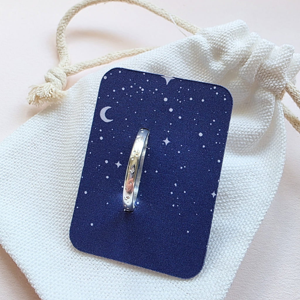 Sterling Silver ring with hand stamped star pattern on a light gray stone surface