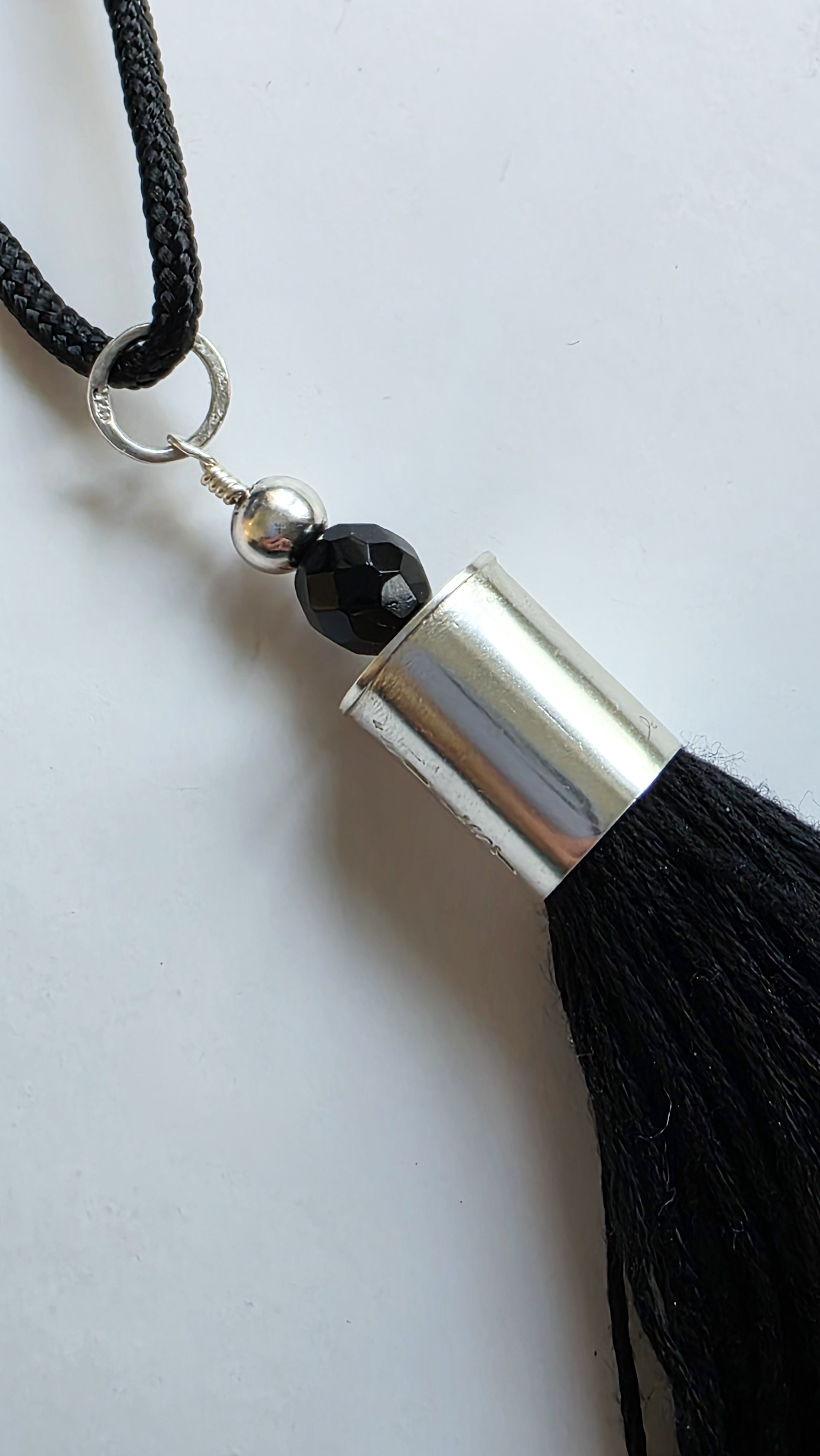 Black tassel necklace with silver accent on a white background