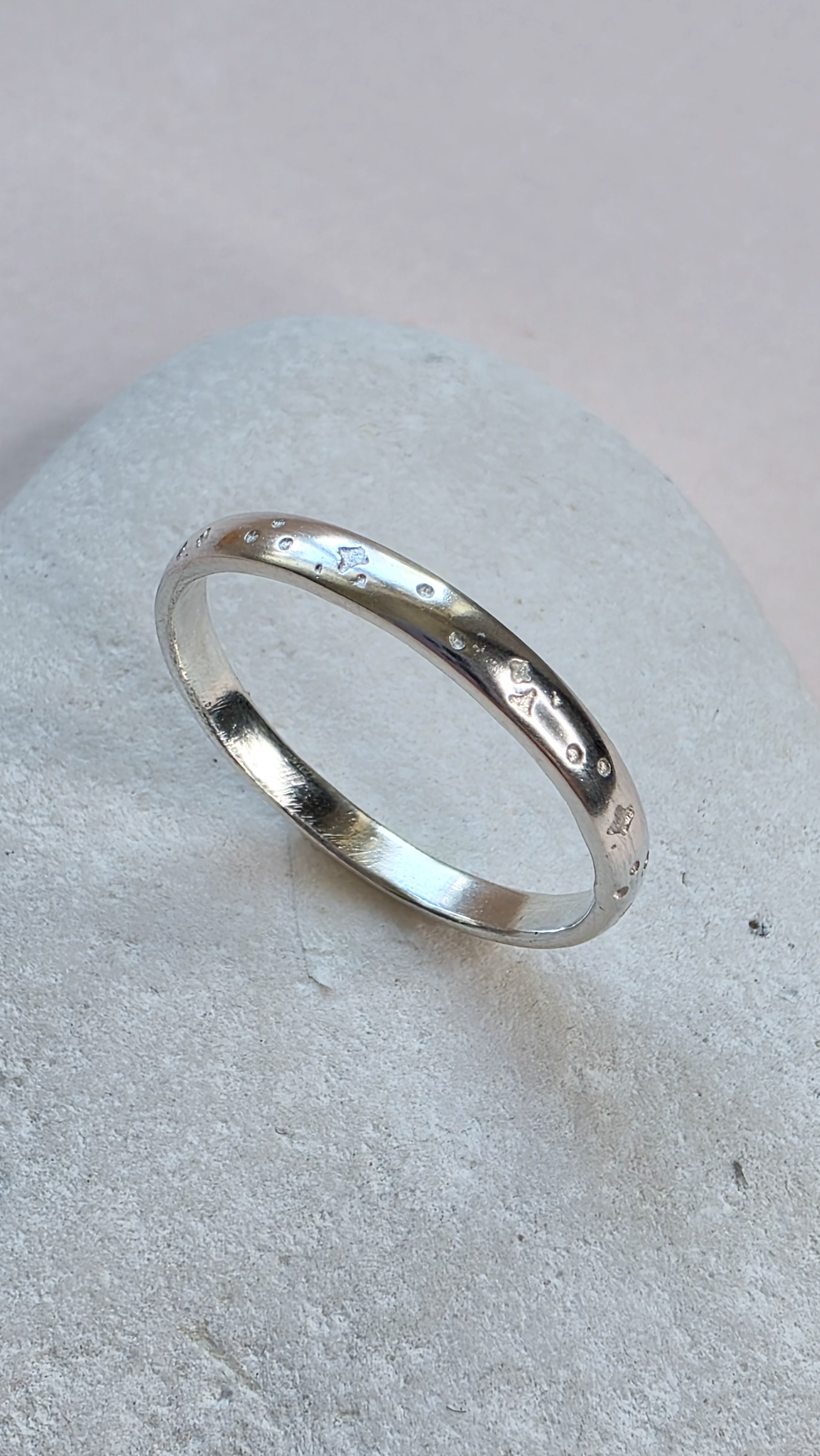 Sterling Silver ring with hand stamped star pattern on a light gray stone surface