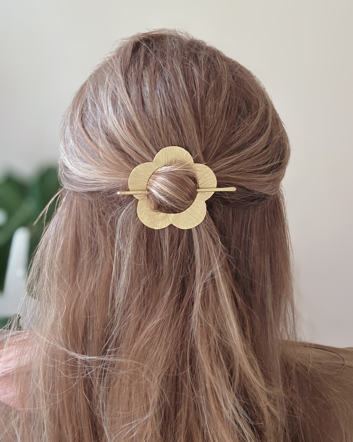 Gold hair clip in a person's hair with a neutral background