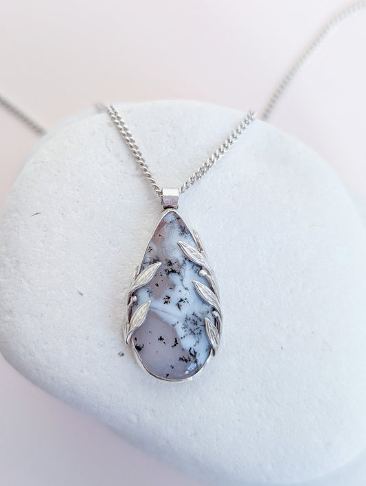 Teardrop-shaped pendant with leaf designs on a white stone